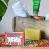 Printed peanut ylang ylang natural soap bar taken out of the cardboard packaging box. Red box with dalmatian style dog illustration on the front. 