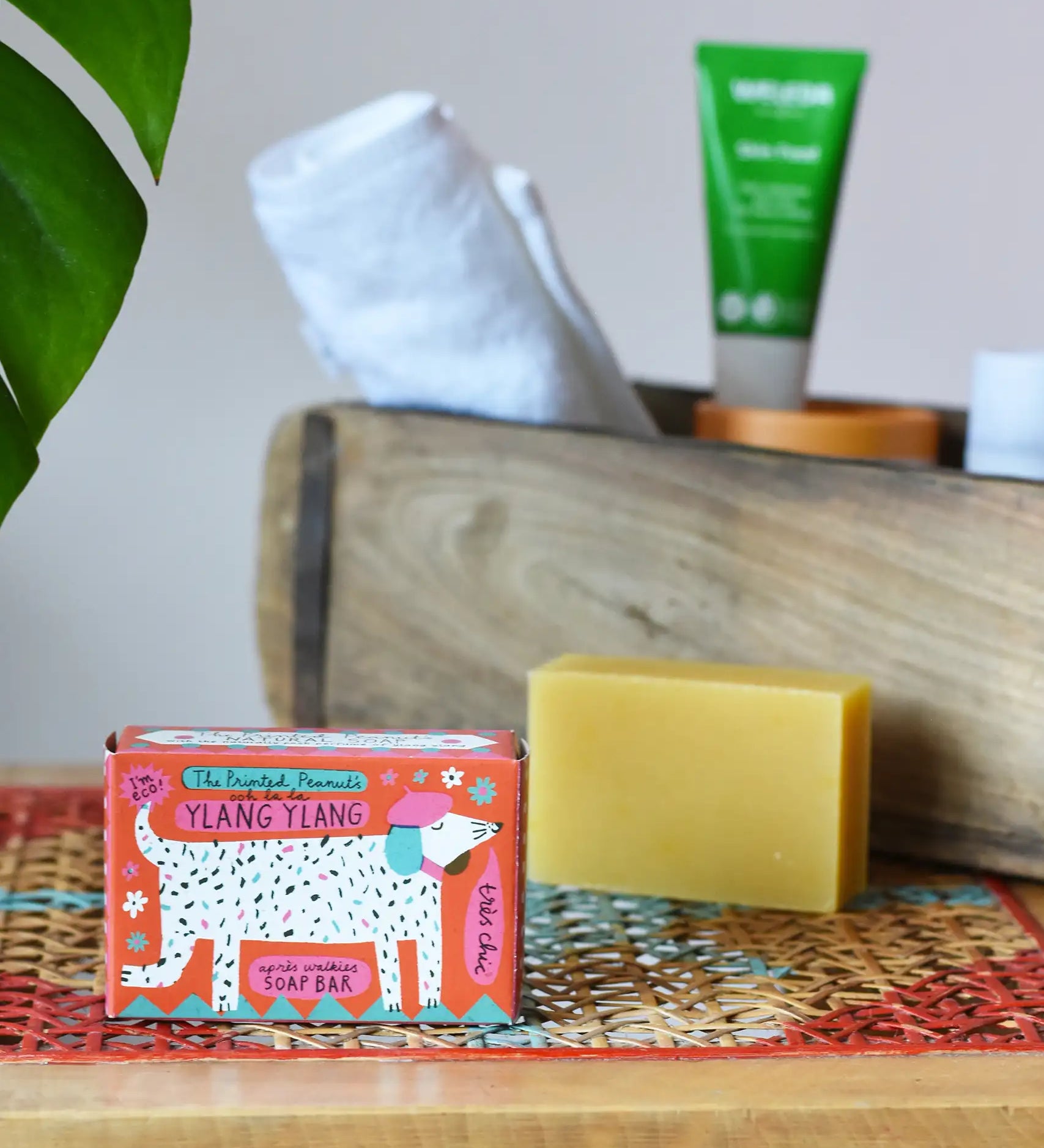 Printed peanut ylang ylang natural soap bar taken out of the cardboard packaging box. Red box with dalmatian style dog illustration on the front. 