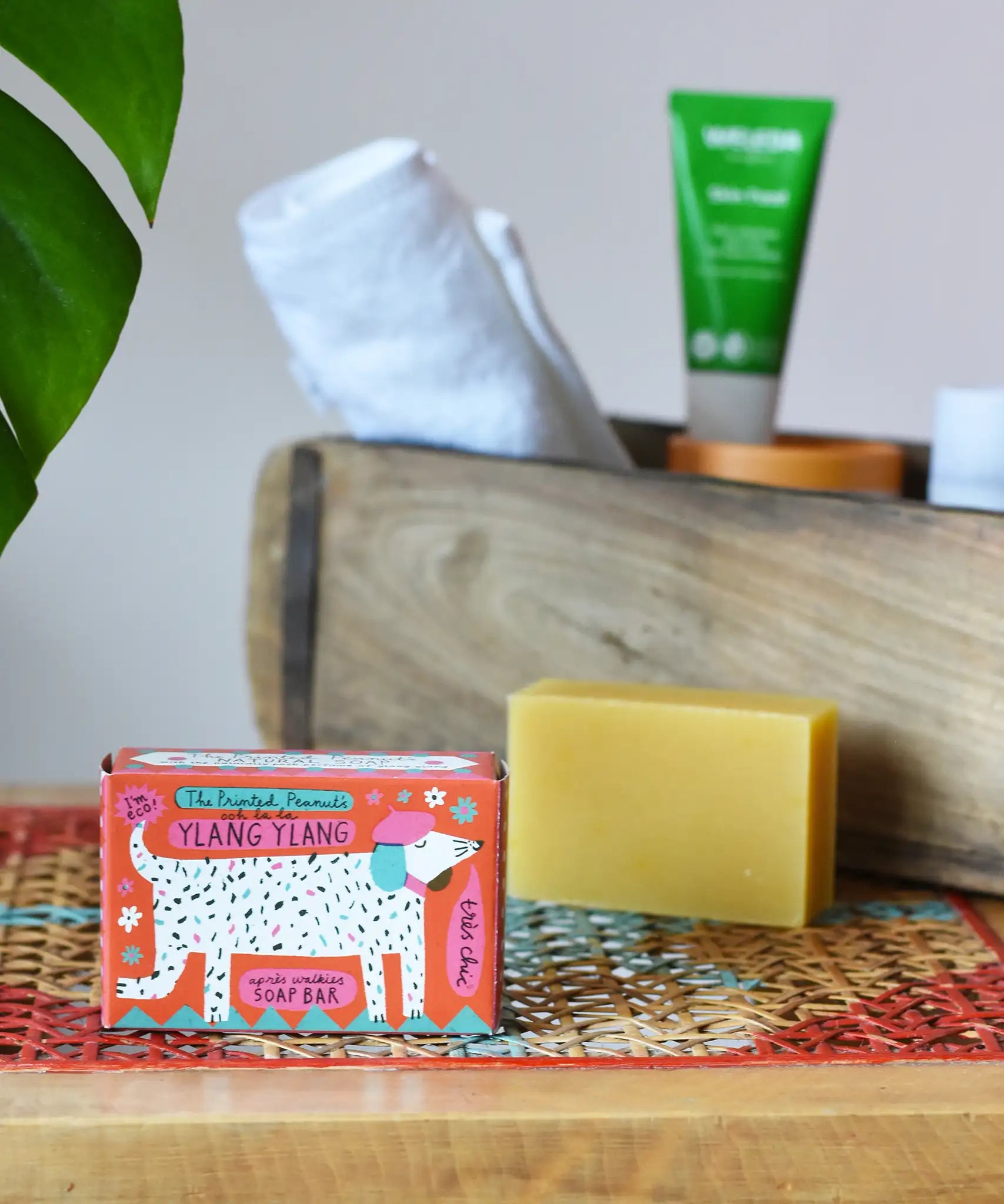 Printed peanut ylang ylang natural soap bar taken out of the cardboard packaging box. Red box with dalmatian style dog illustration on the front. 