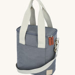 The Lola & Lykke Milk Cooler Bag on a cream background. The bag is denim blue in colour with white carry straps and shoulder strap
