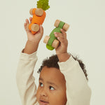 A child holding the Cathy Carot and thr Pepino the Pickle car above their head in their hands