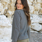A side view of the Rapanui striped  t-shirt in solent oat and navy stripes design worn by a woman. Showing the oat and navy stripe design on organic cotton fabric