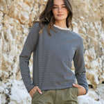 A woman standing outside wearing the Rapanui striped  t-shirt in solent oat and navy stripes design. A heavyweight organic cotton long sleeve top in a relaxed fit style with a oat colour neck trim