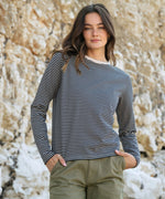 A woman standing outside wearing the Rapanui striped  t-shirt in solent oat and navy stripes design. A heavyweight organic cotton long sleeve top in a relaxed fit style with a oat colour neck trim