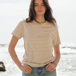A woman standing outside wearing the Rapanui striped t-shirt in a taupe stripe design. A organic cotton short sleeve top in a relaxed fit style. 
