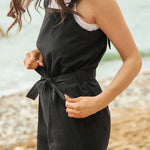 A close up of the black Rapanui jumpsuit showing the black belt tie and pocket detail on organic cotton fabric