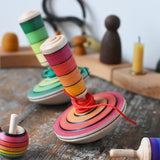 Mader wooden my first spinning top toy with starter in red placed on a wooden surface in the Babipur playroom with other Mader toys.