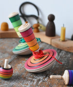 Mader wooden my first spinning top toy with starter in red placed on a wooden surface in the Babipur playroom with other Mader toys.