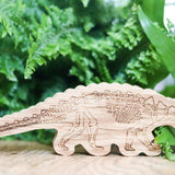 Reel wood eco-friendly wooden ankylosaurus dinosaur figure stood in front of a green plant