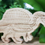 Close up of the plastic free eco-friendly reel wood spinosaurus dinosaur figure in front of a green plant