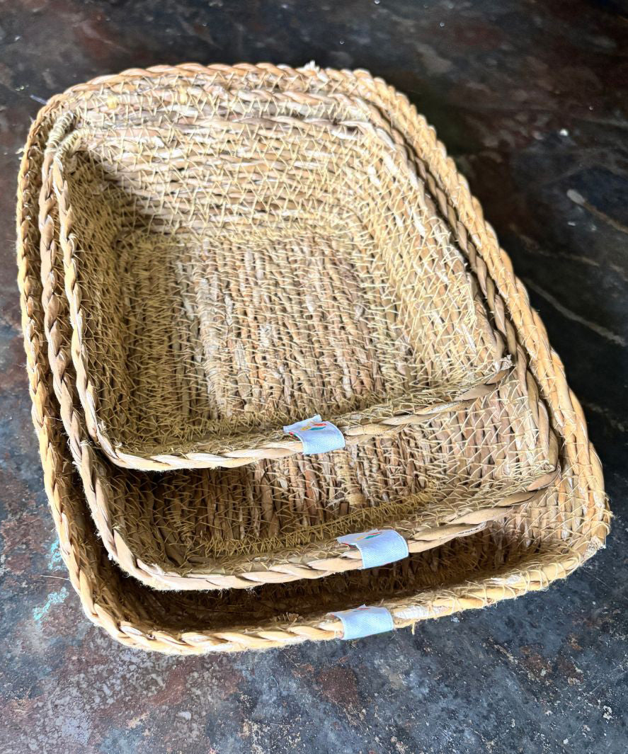 A close up view of the Respiin rectangular seagrass baskets inside eachother on top of a stone surface showing the woven detail. 