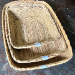A close up view of the Respiin rectangular seagrass baskets inside eachother on top of a stone surface showing the woven detail. 