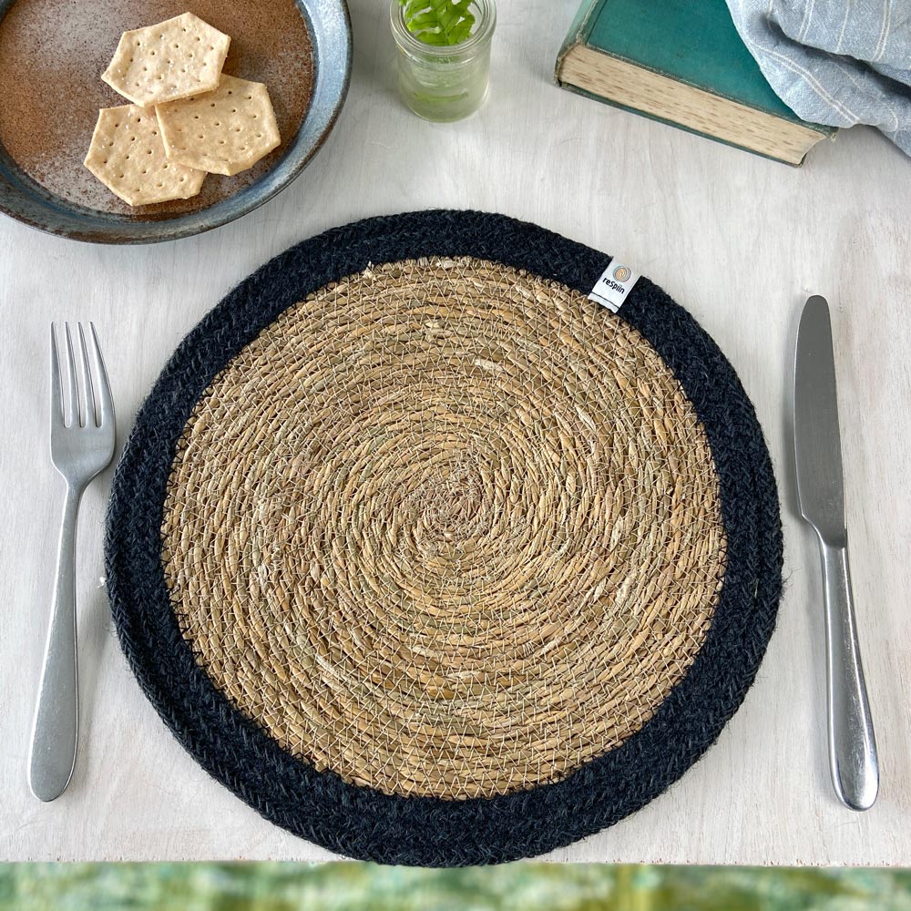 The ReSpiin seagrass and jute natural tablemat with a black coloured ring, laid on a table.