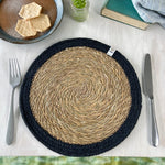 The ReSpiin seagrass and jute natural tablemat with a black coloured ring, laid on a table.