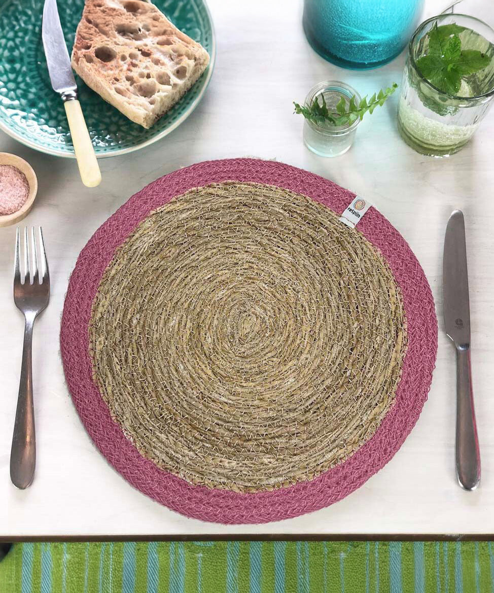 The ReSpiin jute and seagrass handmade table mat in pink, laid on a set table.