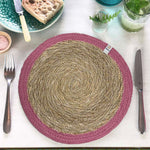 The ReSpiin jute and seagrass handmade table mat in pink, laid on a set table.