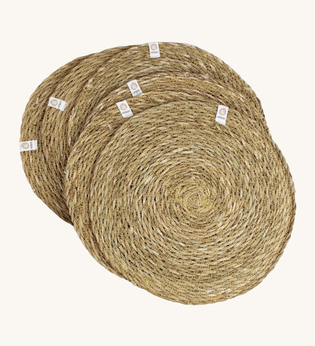 A set of 6 Respiin seagrass tablemat in natural with a matching holder. Features a brand patch stitched on the rim.