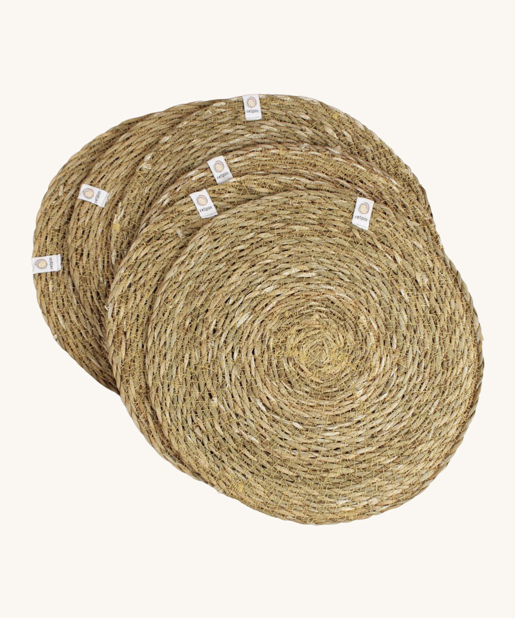 A set of 6 Respiin seagrass tablemat in natural with a matching holder. Features a brand patch stitched on the rim.