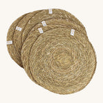 A set of 6 Respiin seagrass tablemat in natural with a matching holder. Features a brand patch stitched on the rim.