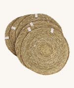 A set of 6 Respiin seagrass tablemat in natural with a matching holder. Features a brand patch stitched on the rim.