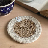 ReSpiin natural jute coaster with white rim on a table next to a book and cup of coffee