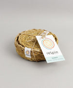 A close up view of the Respiin seagrass coasters inside the matching holder tied up with string. 