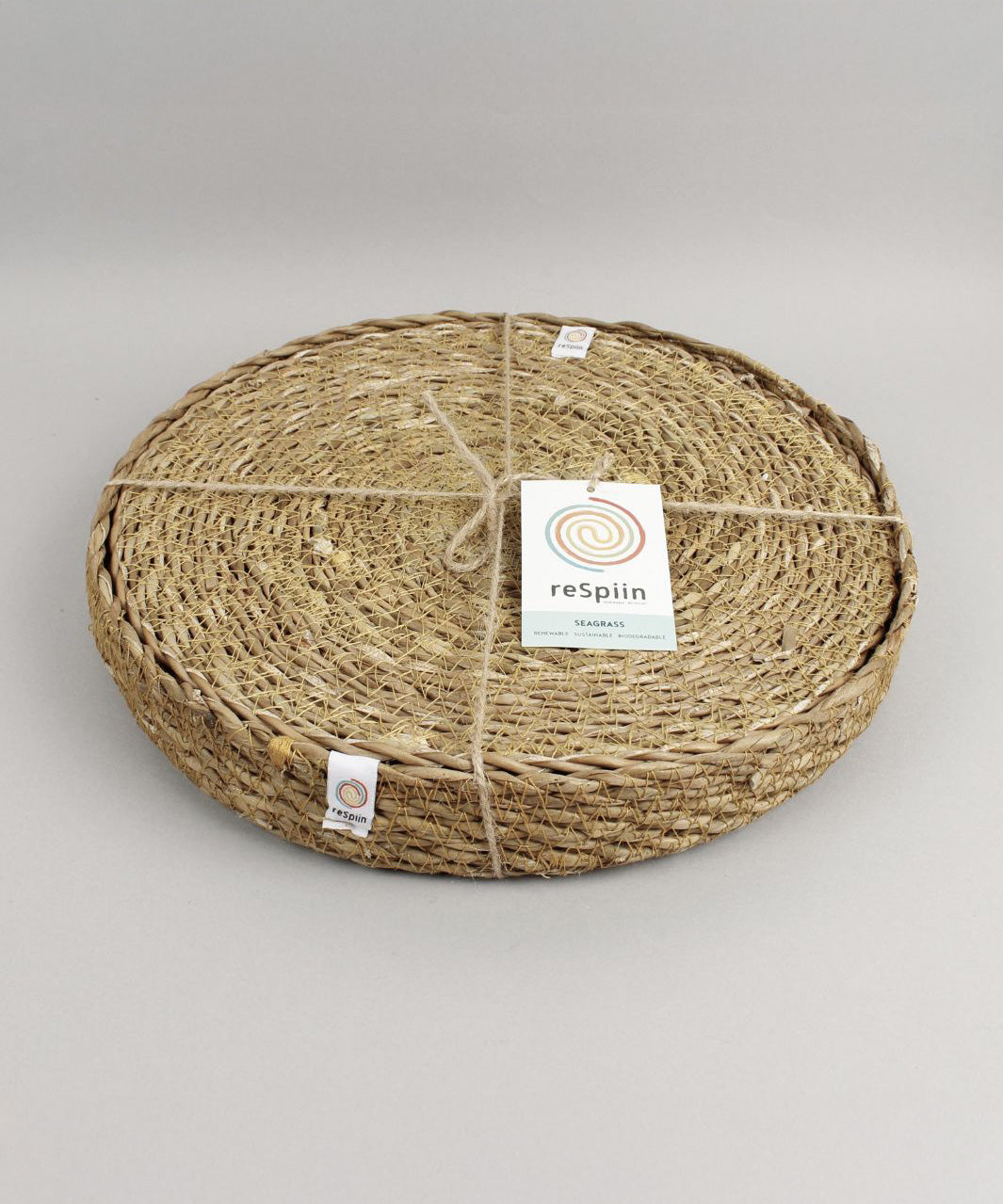 A close up view of the Respiin seagrass tablemat inside the matching holder tied up with string. 