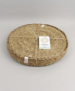 A close up view of the Respiin seagrass tablemat inside the matching holder tied up with string. 