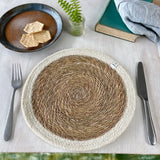 A Respiin jute table mat with white rim from the natural set on a table in between a knife and fork  