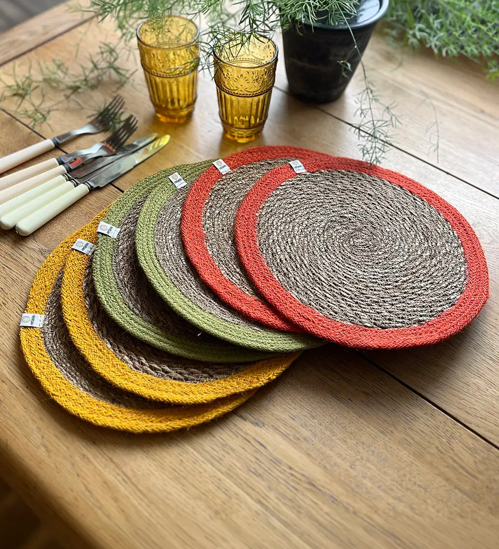 Respiin set of 6 bright jute table mats on a wooden dining table showing a orange, green and yellow rim on each mat 