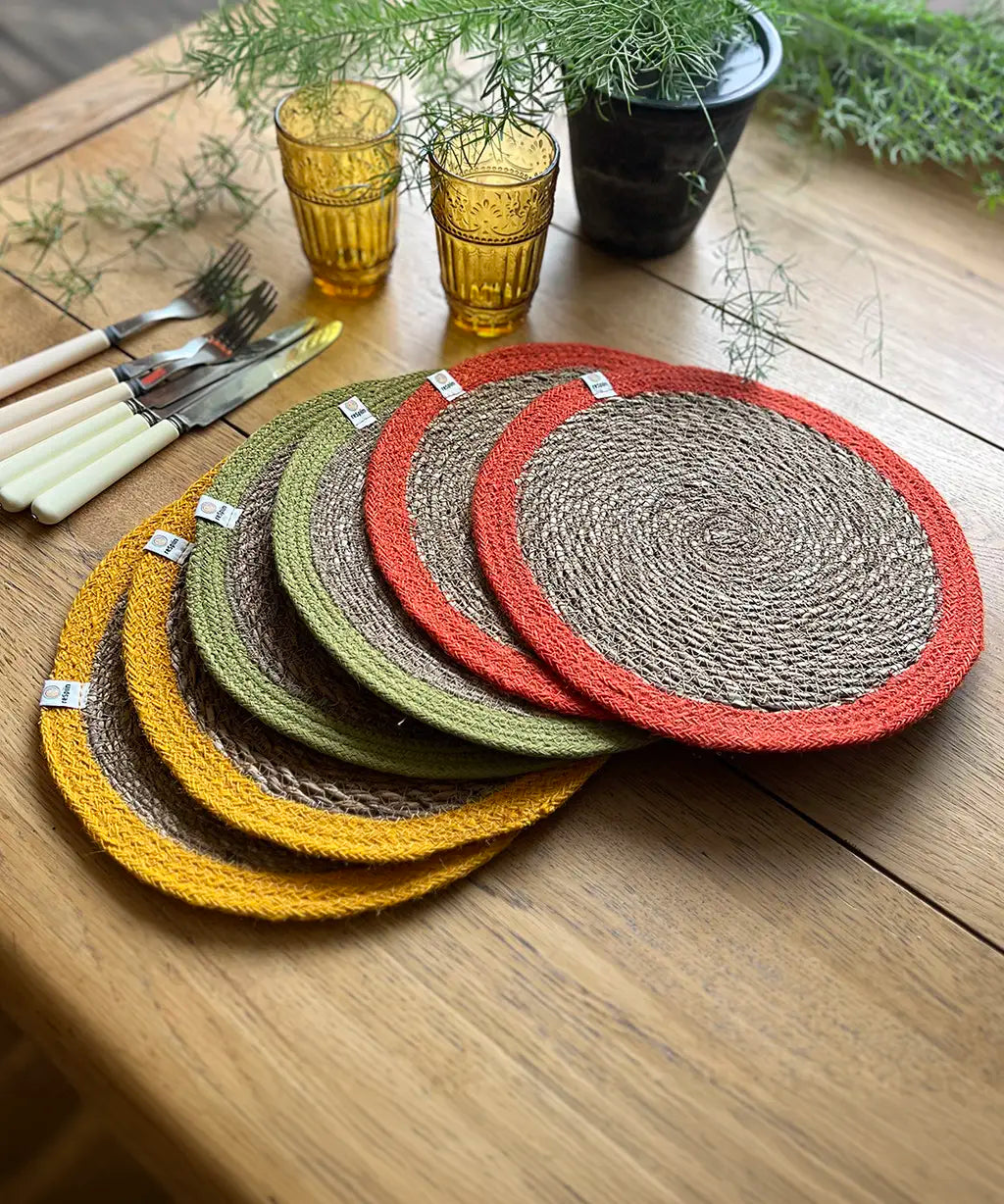 Respiin set of 6 bright jute table mats on a wooden dining table showing a orange, green and yellow rim on each mat 