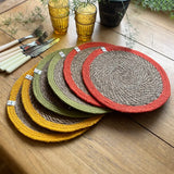 Respiin set of 6 bright jute table mats on a wooden dining table showing a orange, green and yellow rim on each mat 