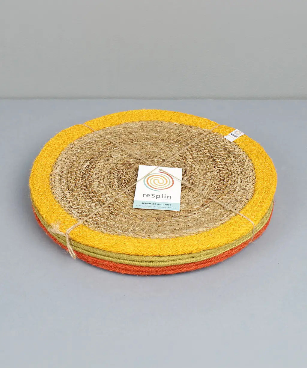 Stack of Respiin set of 6 jute table mats with a yellow, green and orange trim held with yarn
