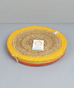 Stack of Respiin set of 6 jute table mats with a yellow, green and orange trim held with yarn