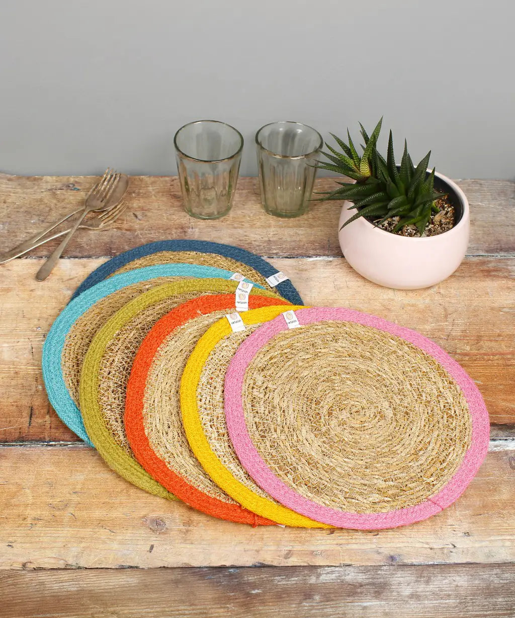 Set of 6 Respiin jute table mats with a bright rainbow inspired edging on a wooden table