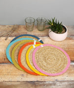 Set of 6 Respiin jute table mats with a bright rainbow inspired edging on a wooden table