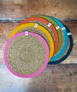 Respiin set of 6 jute table mats with rainbow inspired colours on the rim laid flat on a wooden table