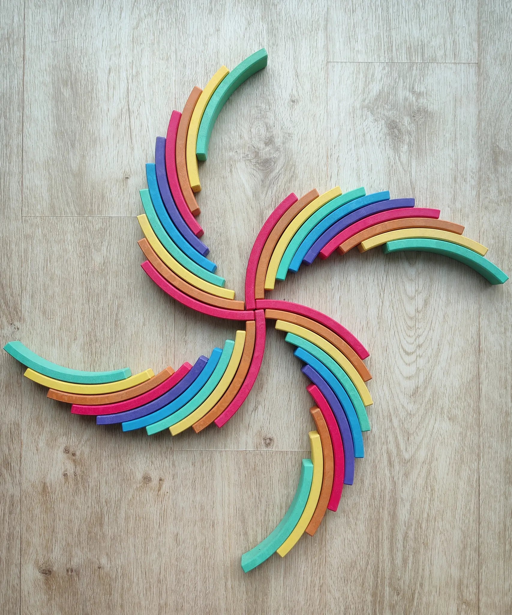 Abel blocks mini rewood Rainbow wooden stacking blocks placed in a pattern on a wooden surface.