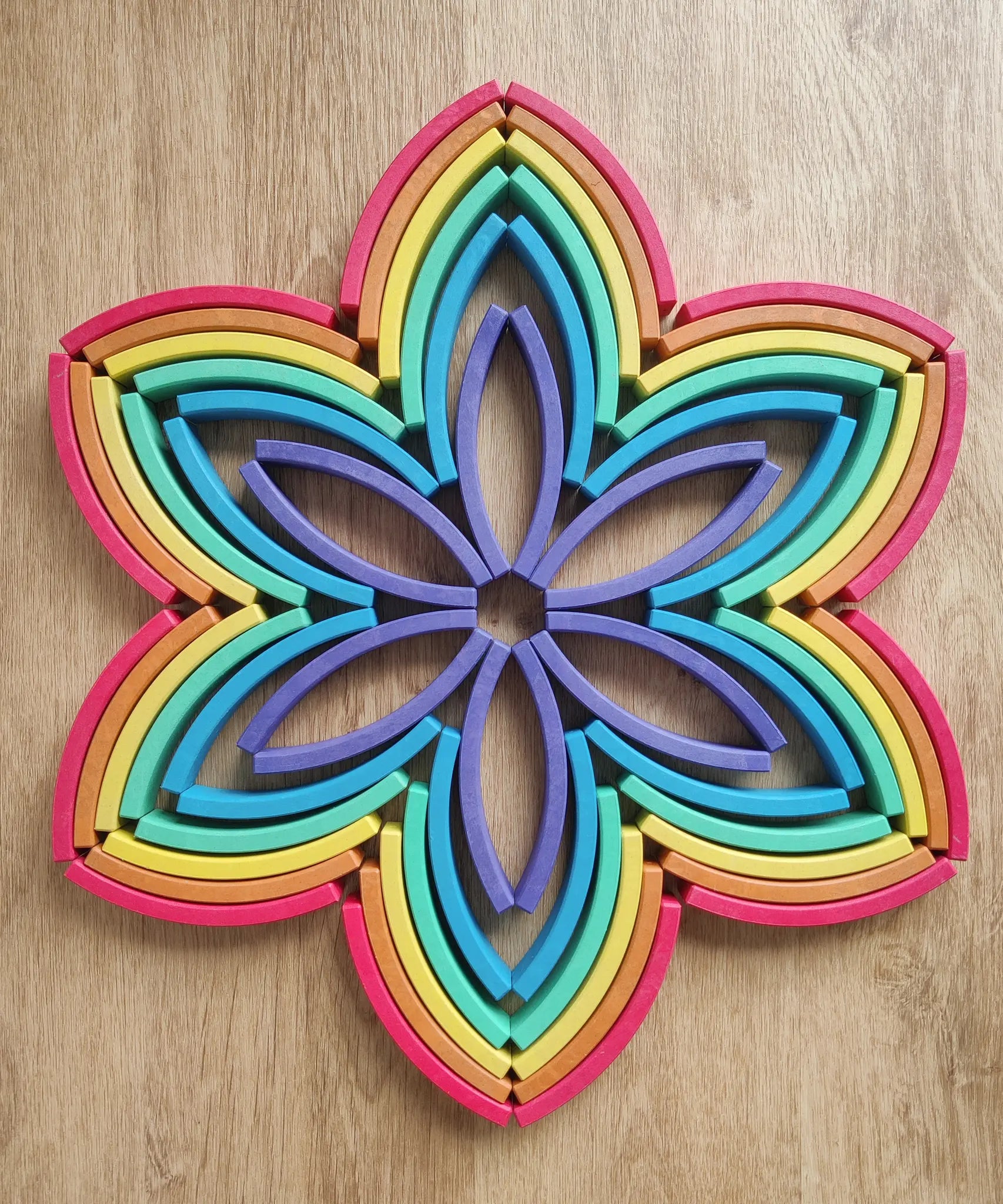 Abel blocks mini rewood Rainbow wooden stacking blocks placed in a flower pattern.
