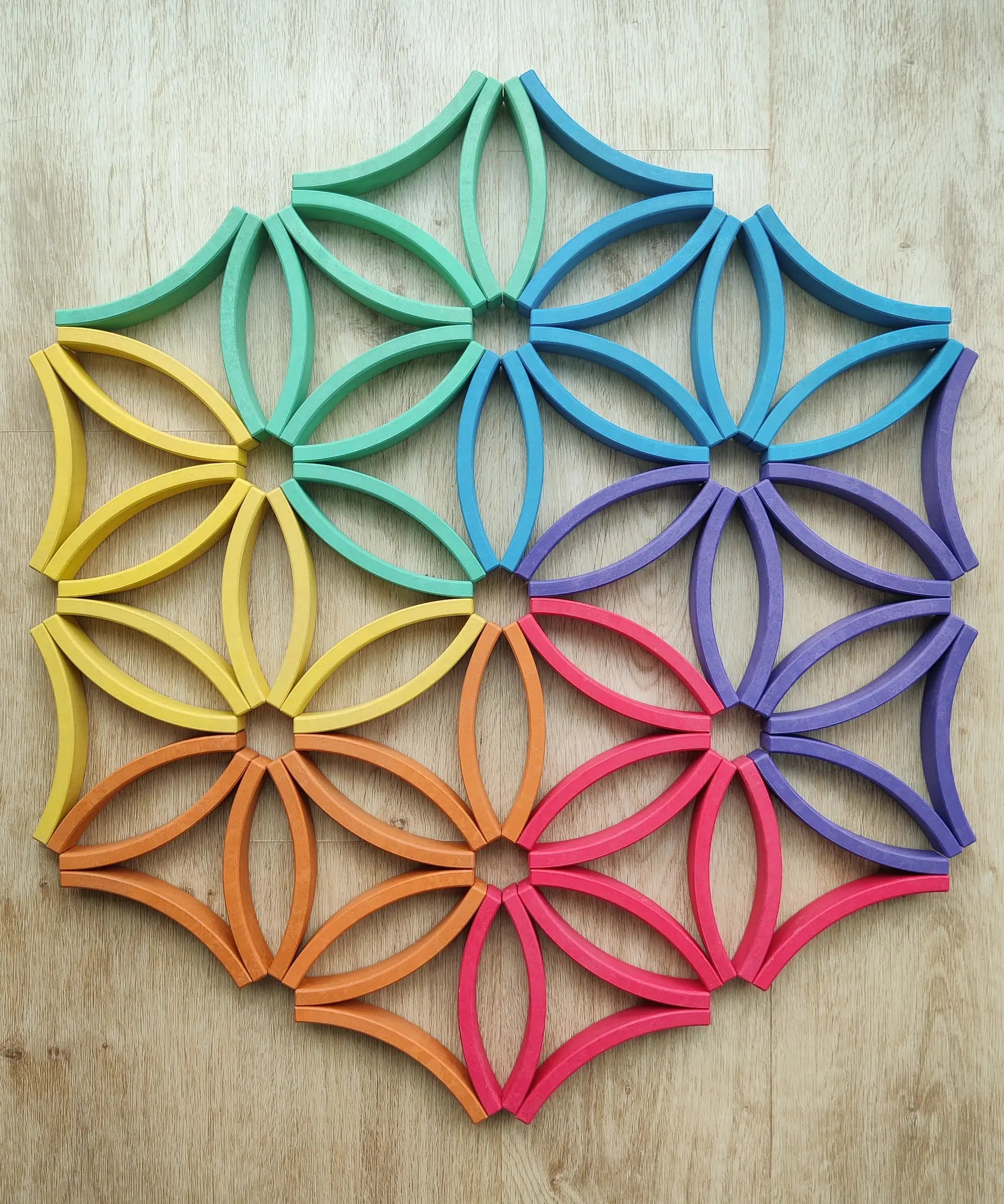Abel blocks mini rewood Rainbow wooden stacking blocks placed on the floor to create a floral mandala.