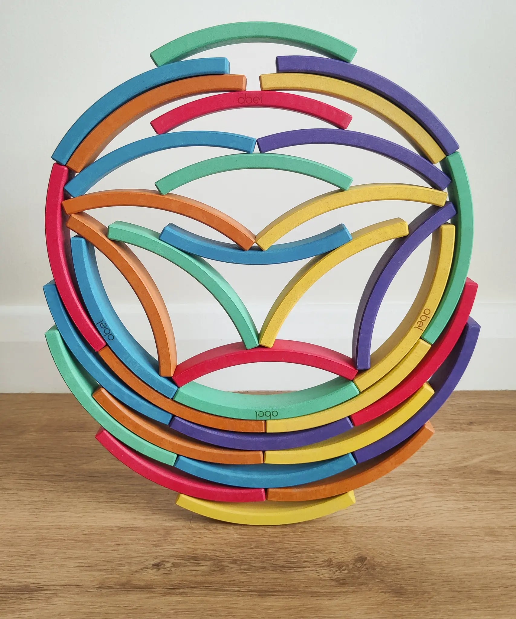 Abel blocks mini rewood Rainbow wooden stacking blocks stacked and balanced on each other.