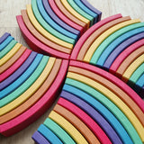 Abel blocks mini rewood Rainbow wooden stacking blocks arranged in pattern on a light wood floor.