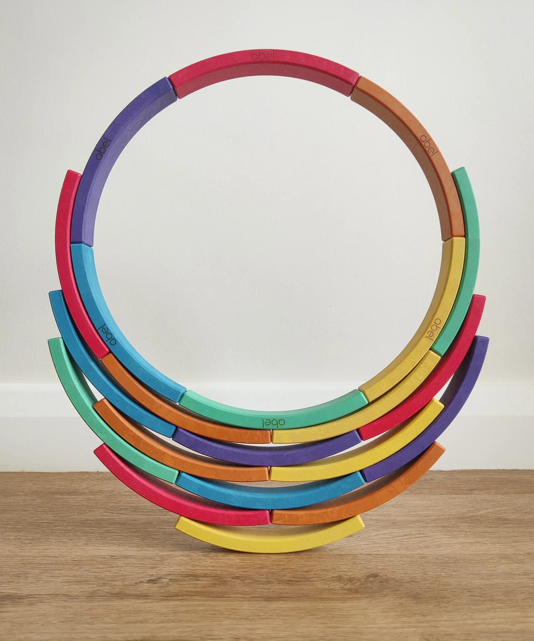 Abel blocks mini rewood Rainbow wooden stacking blocks stacked to create a circle balanced on more blocks.