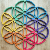 Abel blocks mini rewood Rainbow wooden stacking blocks placed on a wooden surface to form a mandala like pattern.