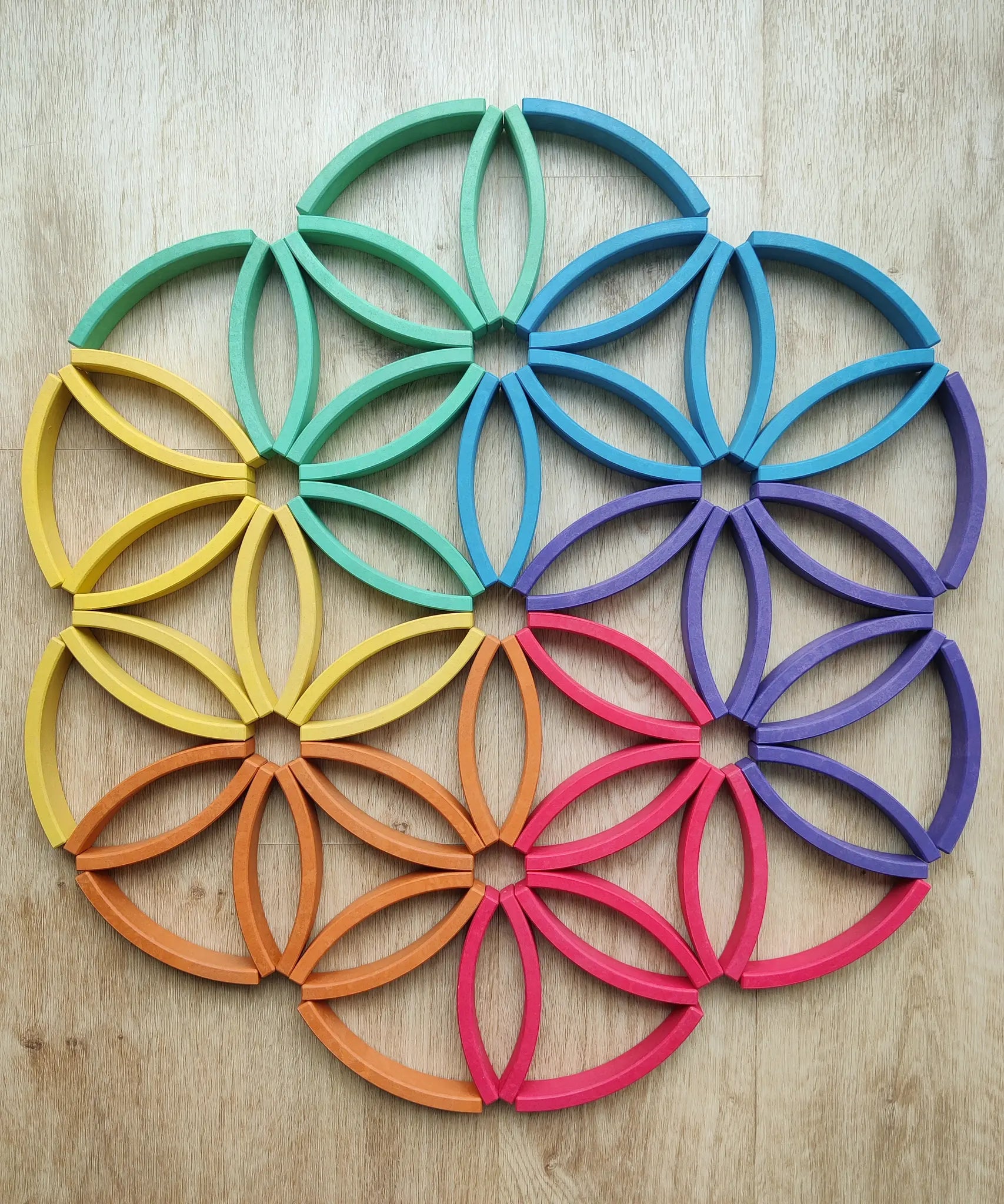 Abel blocks mini rewood Rainbow wooden stacking blocks placed on a wooden surface to form a mandala like pattern.