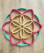 Abel blocks mini rewood Rainbow wooden stacking blocks placed in a flower like mandala pattern.