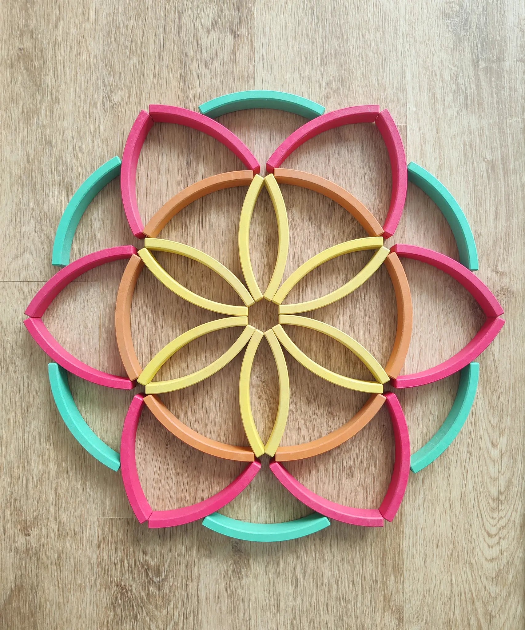 Abel blocks mini rewood Rainbow wooden stacking blocks placed in a flower like mandala pattern.