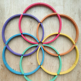 Abel blocks mini rewood Rainbow wooden stacking blocks placed on a wooden surface in circular patterns.