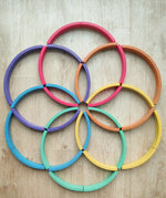 Abel blocks mini rewood Rainbow wooden stacking blocks placed on a wooden surface in circular patterns.