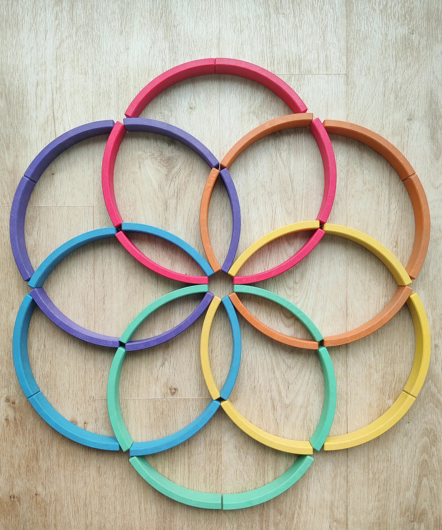 Abel blocks mini rewood Rainbow wooden stacking blocks placed on a wooden surface in circular patterns.